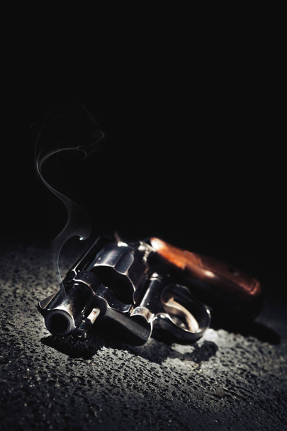 Pistole mit Rauch auf dem Boden, kontrastreiches Bild - Foto, Bild