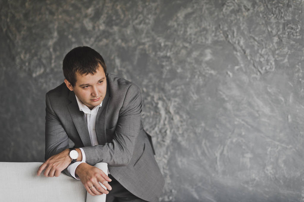 Портрет бизнесмена в костюме на фоне серой оси
 - Фото, изображение