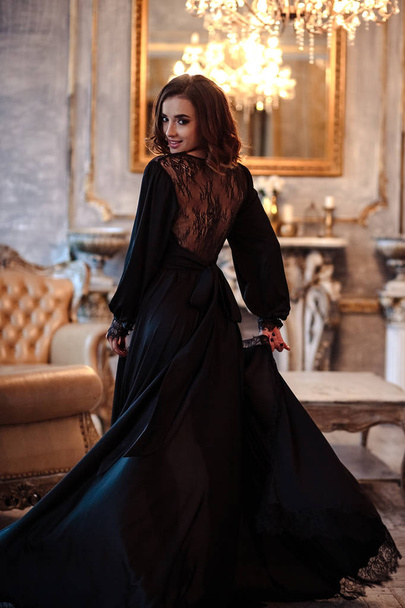 Sensual young woman in a black boudoir dress in classic interior - Foto, afbeelding