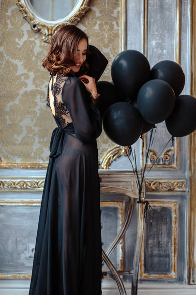 Sensual young woman in a black boudoir dress in classic interior - Foto, immagini