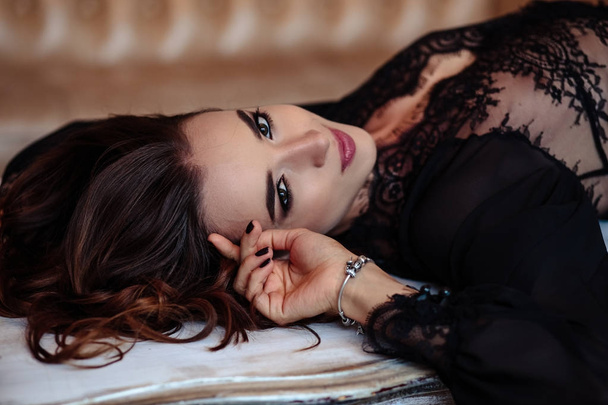 Sensual young woman in a black boudoir dress in classic interior - Fotó, kép