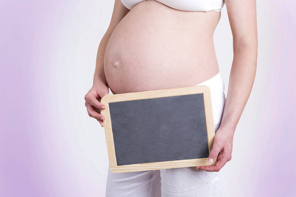 Donna incinta con una lavagna vuota davanti a uno sfondo blu
 - Foto, immagini