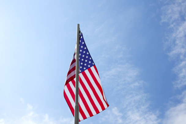 Flagge der Vereinigten Staaten auf einem Fahnenmast vor blauem Himmel - Foto, Bild
