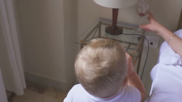A one year old kid drinks milk, and his mother drinks wine. The concept of a dysfunctional family and alcoholism - Záběry, video
