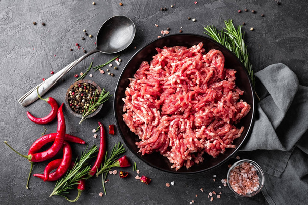 Mince. Ground meat with ingredients for cooking on black background. Top view - Foto, Imagem