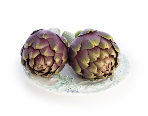 Two purple artichokes ready to cook on old plate - Photo, image
