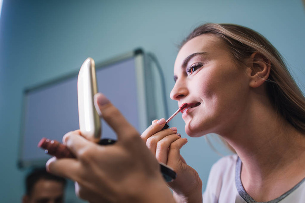 jonge vrouw lippenstift spiegel kijken toe te passen - Foto, afbeelding
