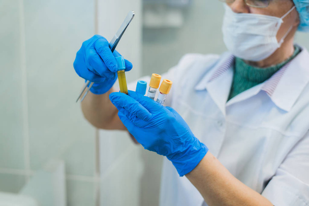 Gros plan d'une chimiste expérimentée installant des tubes sanguins à l'intérieur d'une centrifugeuse pour un test dans un laboratoire
. - Photo, image