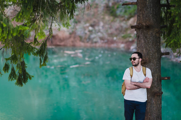 Bearded man model poses alongside a Green water Lake. - Foto, Bild