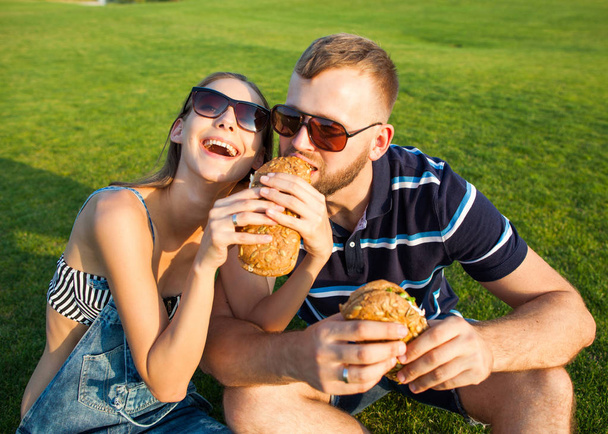 couple in love sitting on the grass in the park and eating sandw - Foto, imagen