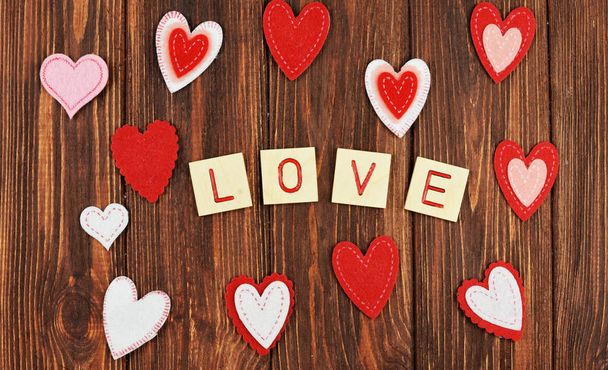 2 月に愛のバレンタインの日、単語の愛の手紙、バレンタインの日に碑文の木製の背景に美しい赤いハート飾りの饗宴します。  - 写真・画像