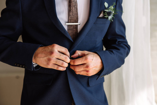 Бизнесмен исправляет кнопки на пиджаке, руки крупным планом, одевание, мужской стиль, корректирует рукава, готовится к свадьбе
 - Фото, изображение