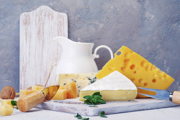 Cheeses and milk on a light old board. Rustic view. - Photo, Image