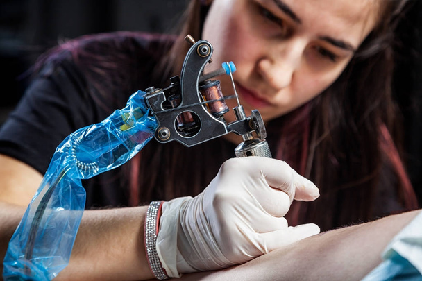 Gyönyörű sötét hajú nő tetováló művész rajz egy tetoválás, tetoválás, közeli, alsó nézet - Fotó, kép