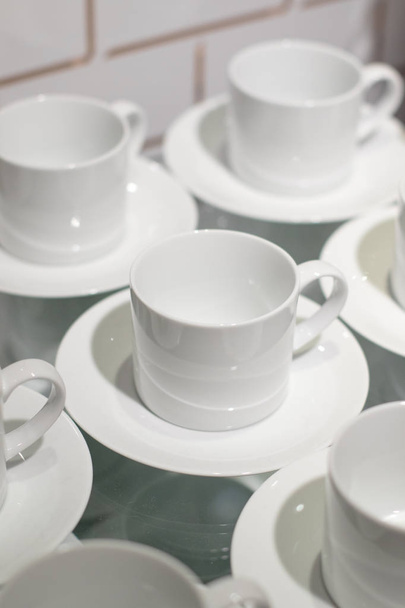 White ceramic cups set on display - Фото, изображение