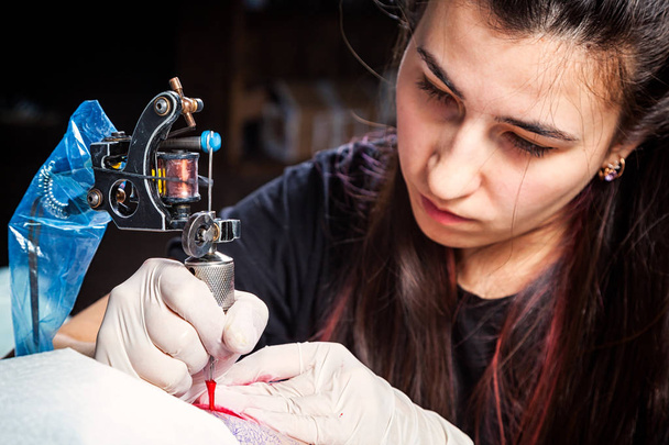 Tetováló művész közelről mutatja a folyamat kezd piros tetoválás.  - Fotó, kép