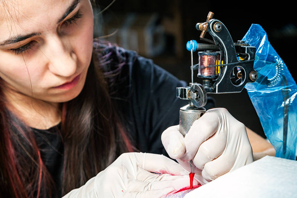 Tetováló művész közelről mutatja a folyamat kezd piros tetoválás.  - Fotó, kép