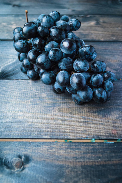 Hromada černých hroznů na modrém ošuntělém dřevěném pozadí - Fotografie, Obrázek
