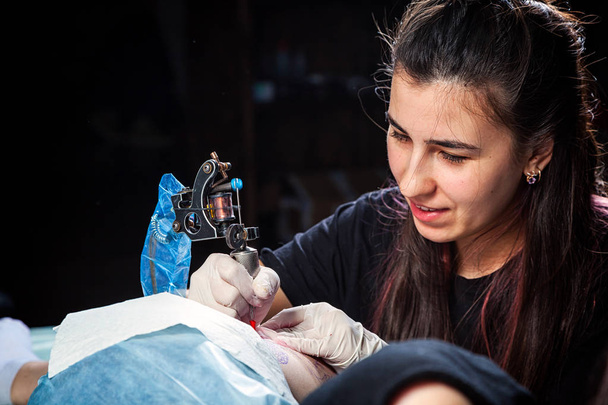Professzionális tetováló művész nő tesz egy tetoválás a combcsont egy fiatal lány - Fotó, kép