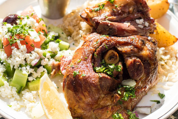 Ζεστό και ζουμερό ψητό αρνί με χωριάτικη σαλάτα. Αυθεντικά ελληνικό φαγητό. - Φωτογραφία, εικόνα