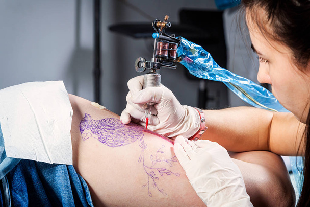 Közelről, a tattooist hogy szakmai művész tetoválás van a test nő használja a gépet munka kreatív design Studio - Fotó, kép