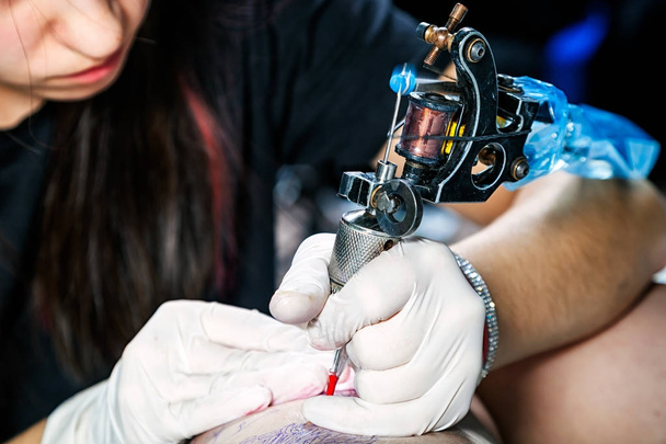 Közelről kezét a gép csinálás a combcsont női madár tetoválás - Fotó, kép