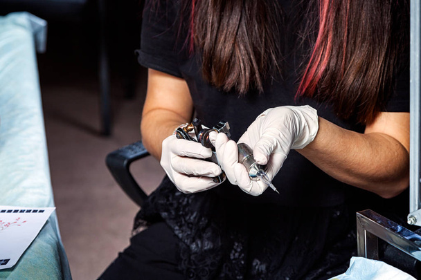 Close up woman tatto master preparing  the tattoo machine at work - Photo, Image