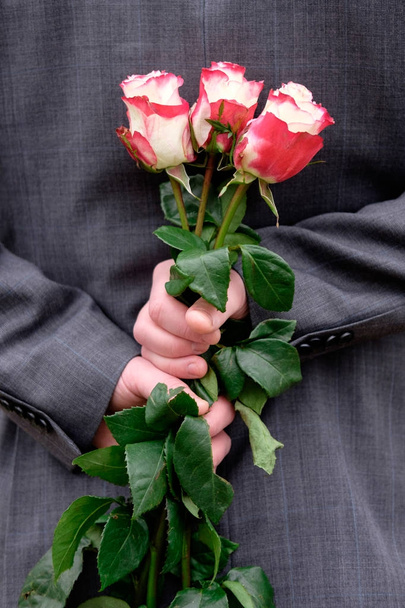 man holding bouquet of roses behind back - 写真・画像