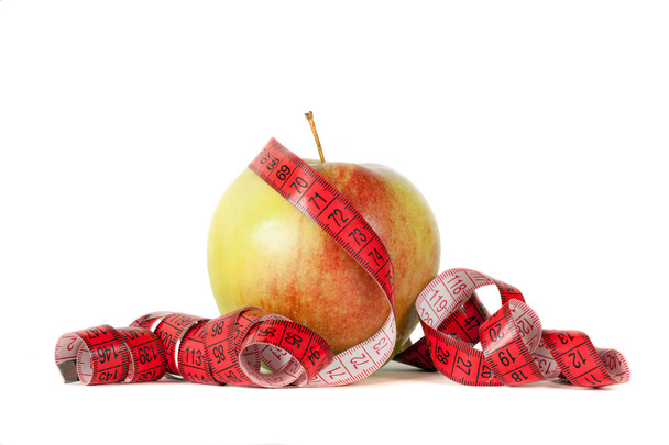 Manzana con cinta métrica sobre fondo blanco
 - Foto, imagen