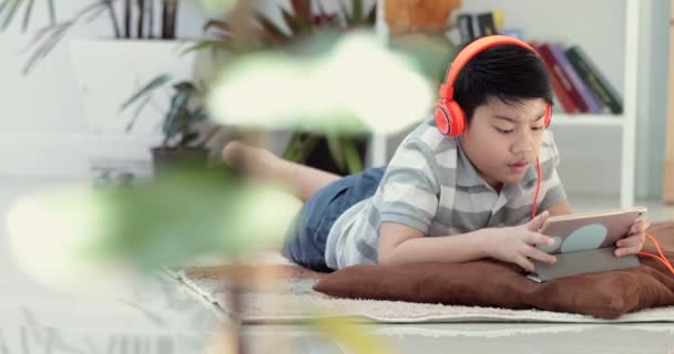Asiático preadolescentes descansan en el suelo y jugar tableta con la cara sonrisa en casa
. - Metraje, vídeo
