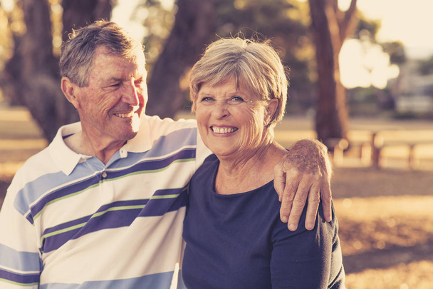 εκλεκτής ποιότητας φίλτρο πορτρέτο της αμερικανικής senior όμορφο και ευτυχισμένο ζευγάρι περίπου 70 ετών δείχνει αγάπη και στοργή χαμογελώντας μαζί στο πάρκο - Φωτογραφία, εικόνα