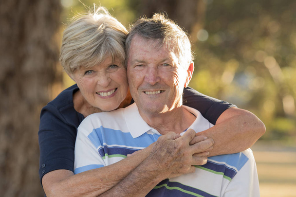 Porträt amerikanischer Senioren schönes und glückliches reifes Paar um die 70 Jahre, das Liebe und Zuneigung zeigt und zusammen im Park lächelt - Foto, Bild