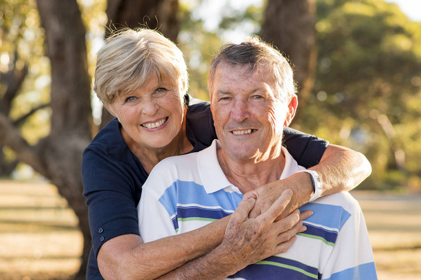 portrait de sénior américain beau et heureux couple d'âge mûr autour de 70 ans montrant l'amour et l'affection souriant ensemble dans le parc
 - Photo, image