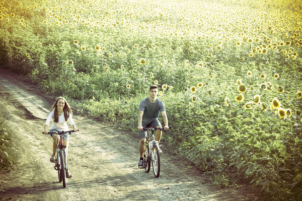 Teenie-Paar fährt Fahrrad in Sonnenblumenfeld - Foto, Bild