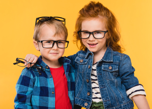 portrait of smiling kids in eyeglasses isolated on yellow - Фото, изображение