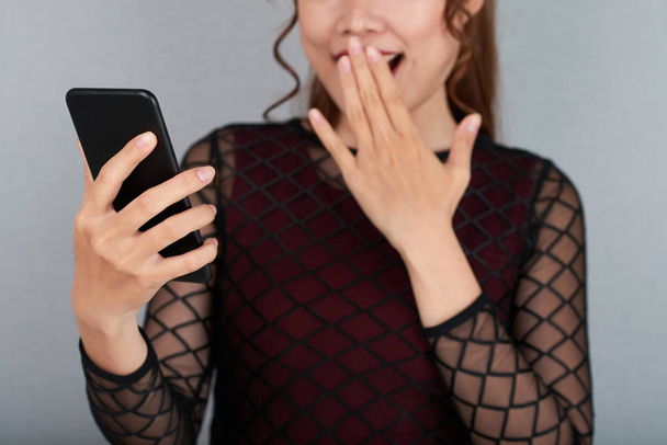 Immagine ritagliata di giovane donna che legge notizie scioccanti sul suo telefono
 - Foto, immagini
