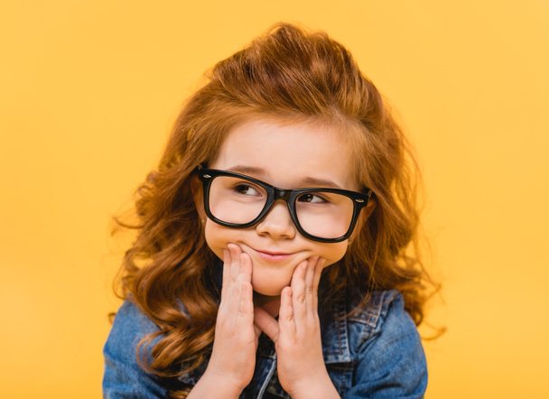 portrait of pensive little kid in eyeglasses isolated on yellow - Photo, Image