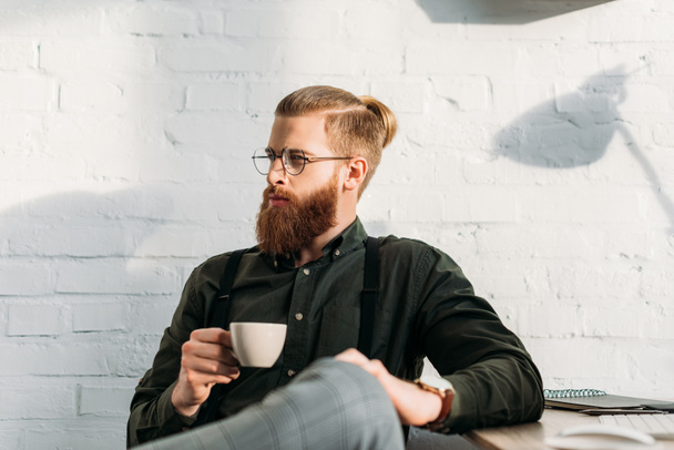 handsome businessman holding cup of coffee and looking away - 写真・画像