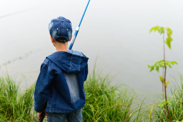 Un ragazzo pescatore sulla riva del fiume con una canna da pesca in mano
 - Foto, immagini