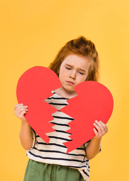 portrait of sad child with broken red paper heart isolated on yellow, st valentines day concept - Фото, изображение