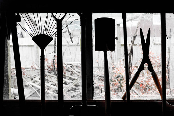 Herramienta de jardín colgada en una ventana del cobertizo
 - Foto, Imagen