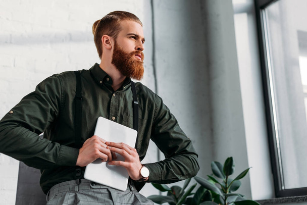 bearded businessman holding tablet and looking away  - 写真・画像
