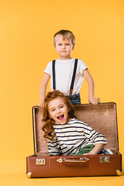 mutlu çocuk çantada yakınındaki üzerinde izole sarı tarafından ayakta çocukla oturuyor - Fotoğraf, Görsel