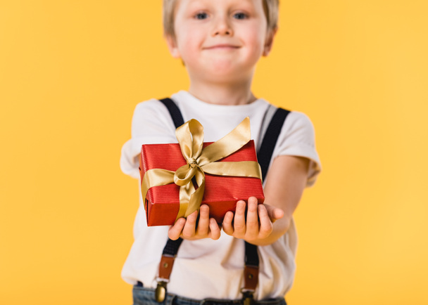 вибірковий фокус маленького хлопчика з загорнутим подарунком ізольовано на жовтому, концепція Дня матері
 - Фото, зображення