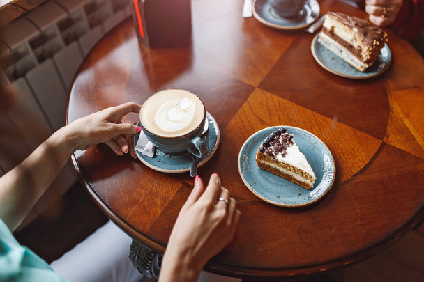 Two women chatting in a coffee shop, cake on the table - Fotoğraf, Görsel