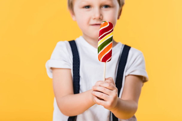 selective focus of adorable little boy with lollipop in hand isolated on yellow - Foto, immagini