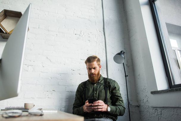 handsome bearded businessman using smartphone in office - Photo, Image