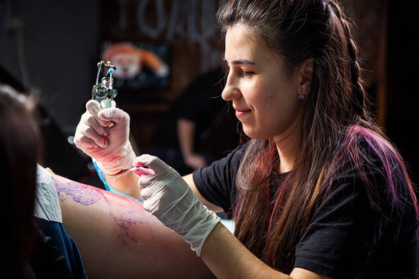 Portréja egy nő tetováló mester mutatja a folyamat létrehozása tetoválás - Fotó, kép