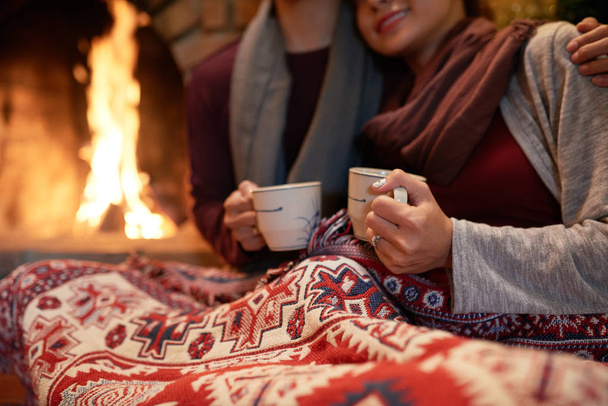Amante pareja bebiendo té caliente cerca de la chimenea en Nochebuena
 - Foto, imagen