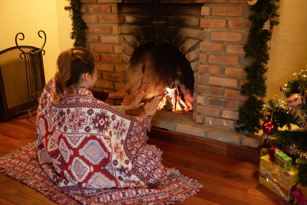 Young couple sitting near fireplace and warming hands on Christmas Eve - Fotografie, Obrázek